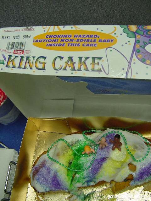 Photo of cake with baby figures and an amusing warning label.